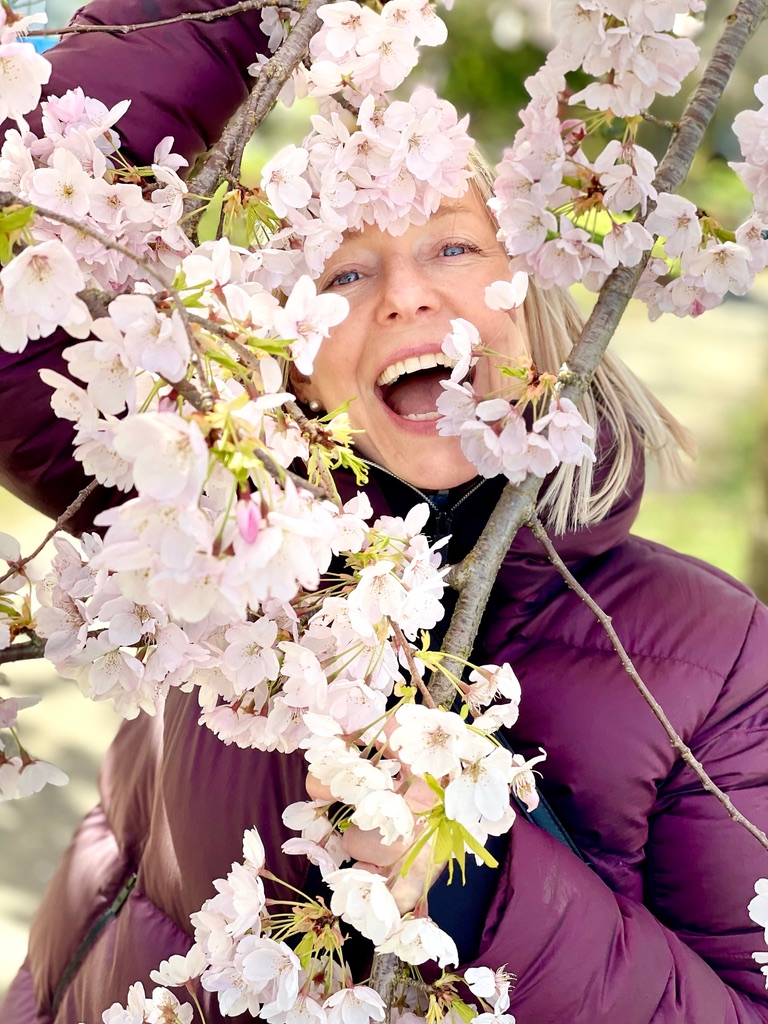 Debbie Collins laughing among cherry blossoms